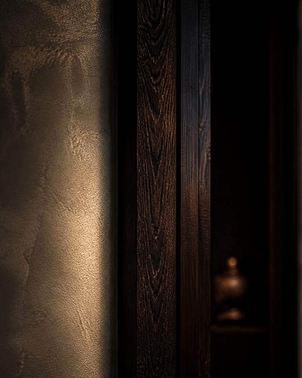 Close-up of a stained oak doorframe against limewash plaster